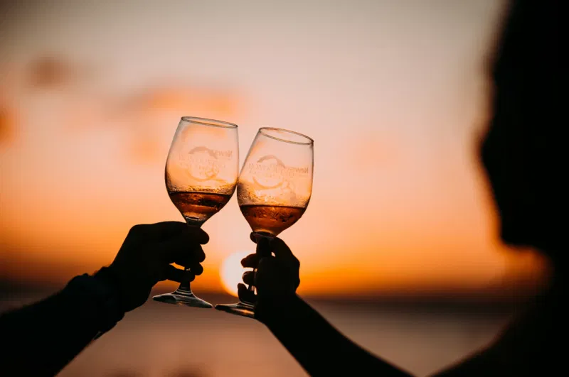 Wine glasses toast at sunset